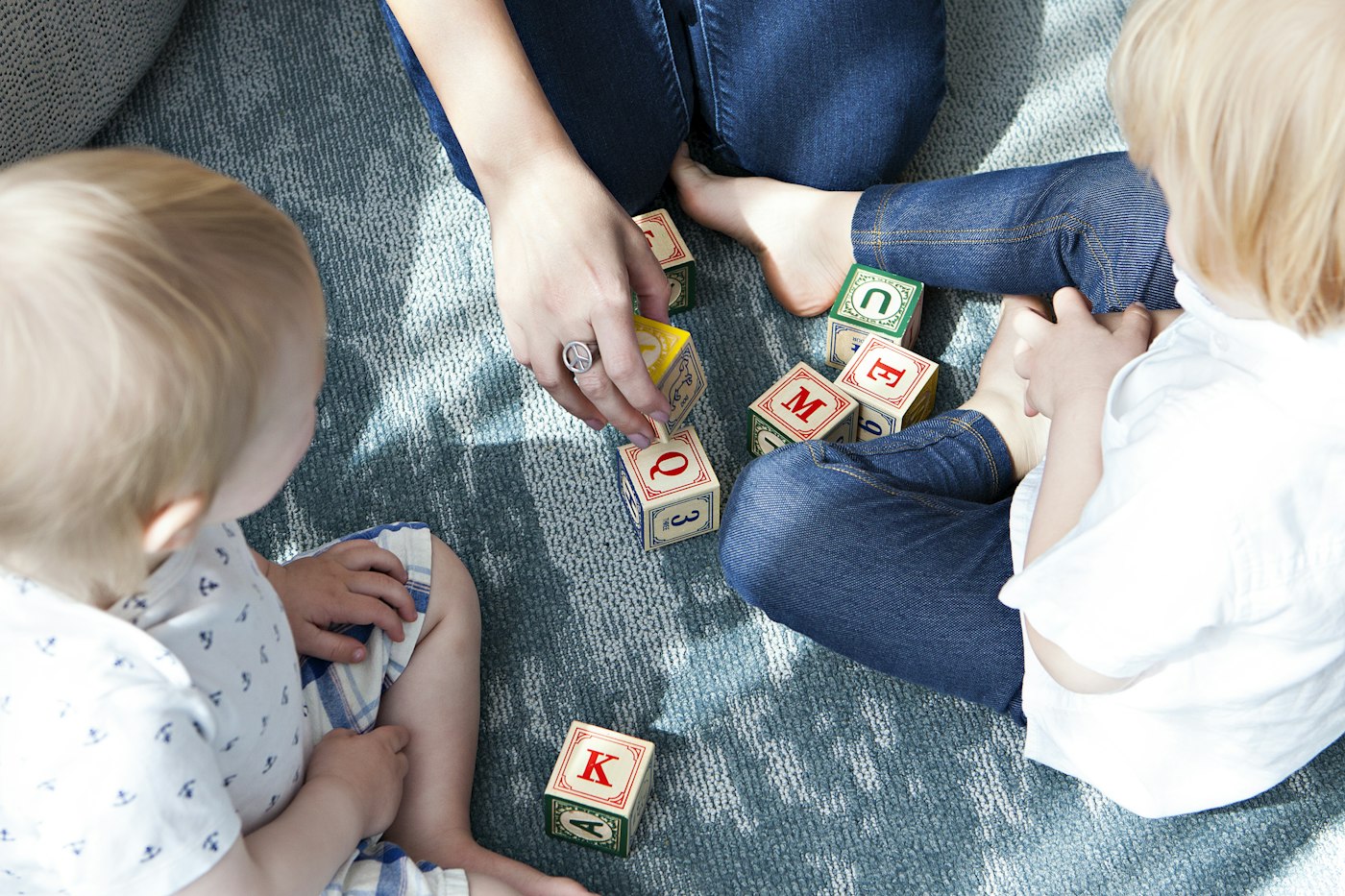 Two toddlers playing with wooden letter blocks