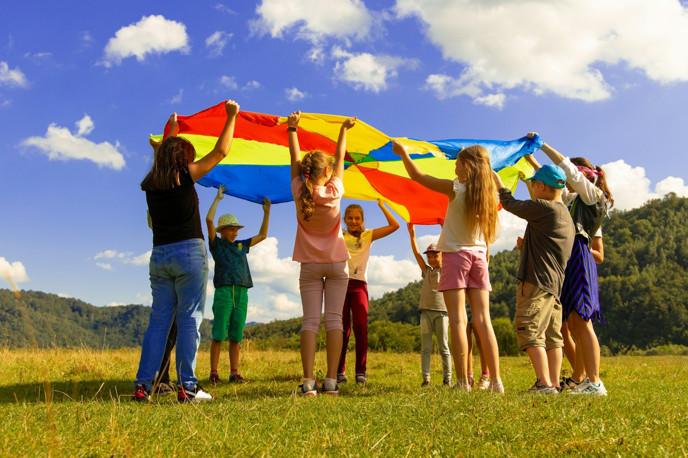 Children playing a parachute game on the grass at a holiday club