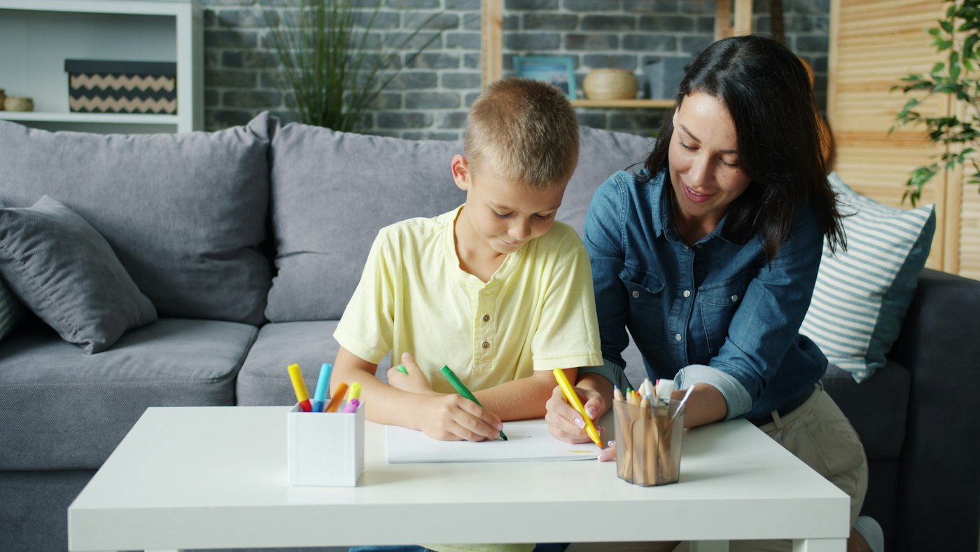 Private tutor helping a boy with his schoolwork at home